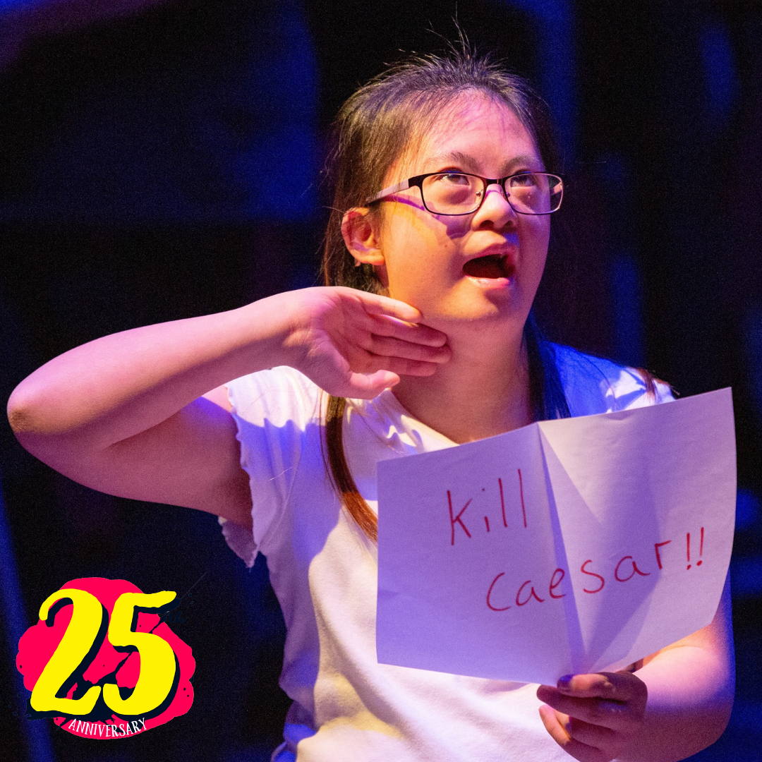A young girl on stage holding a 'Kill Caesar' sign